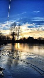 Reflection of trees in water at sunset