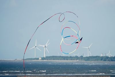 Cranes by sea against clear sky