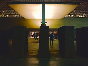 Silhouette people walking in illuminated building