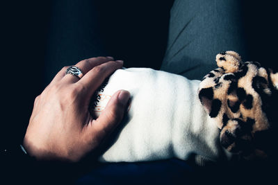 Midsection of woman with dog against black background.holding dog