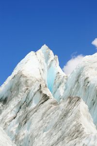 Low angle view of snowcapped mountains against clear blue sky