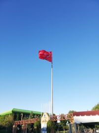 Low angle view of flag against clear blue sky