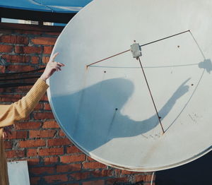 Cropped image of hand against satellite dish
