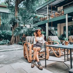 Woman sitting on chair against plants