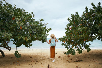 Woman standing by tree against sky