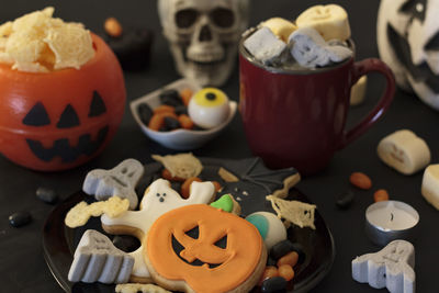 Halloween party table with snacks, cookies, treats, hot drink and halloween decoration