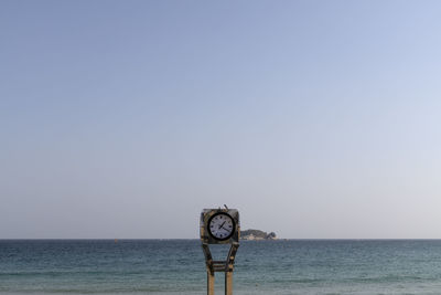 Ferris wheel by sea against clear sky