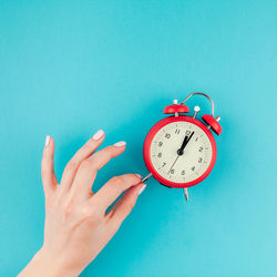 Close-up of woman with alarm clock against blue background