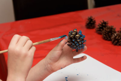 Cropped image of kid painting pine cone