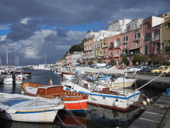 Boats moored in harbor against buildings in city