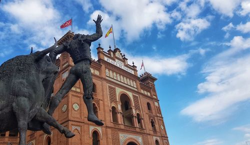 Low angle view of statue of building against cloudy sky