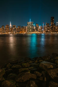 Illuminated city by buildings against sky at night