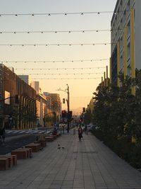 People in city against clear sky during sunset