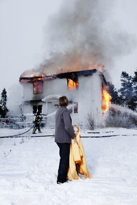 Grandmother holding rescued girl, burning building in background