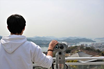 Rear view of man photographing cityscape against sky