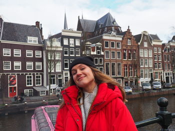 Portrait of smiling woman standing against buildings in winter