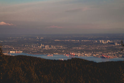 High angle view of city by sea against sky at sunset