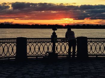 Silhouette people looking at sea against sky during sunset