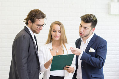 Business colleagues discussing over document while standing in office