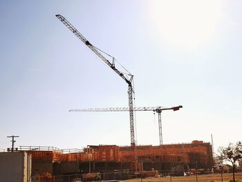 Low angle view of cranes at construction site against sky