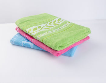 High angle view of colorful towels stacked on table against white background