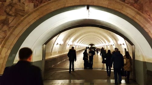 Rear view of silhouette people in illuminated tunnel