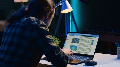 Rear view of man using laptop at office