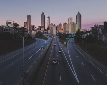 Vehicles on road amidst buildings in city against sky