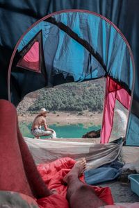 Low section of man in tent against lake