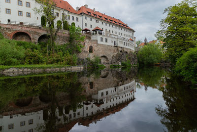 Arch bridge over river by buildings against sky