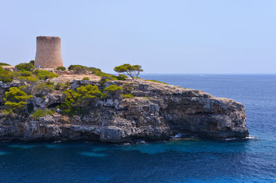 Rocks by sea against clear sky