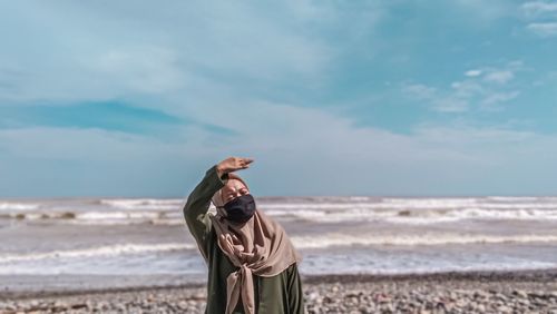 Man standing at beach against sky