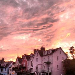 Houses against cloudy sky at sunset