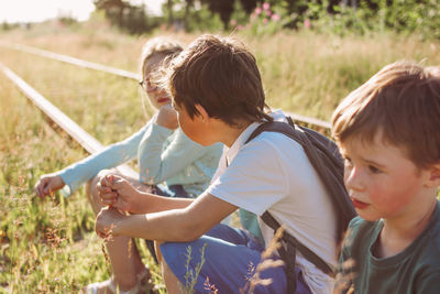 Cute kids sitting on field outdoors