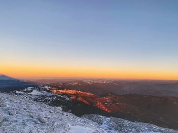 Scenic view of snowcapped mountains against clear sky during sunset