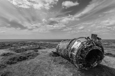 Abandoned metallic structure on beach against sky