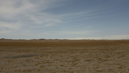 Scenic view of desert against sky with ice mountain in background 