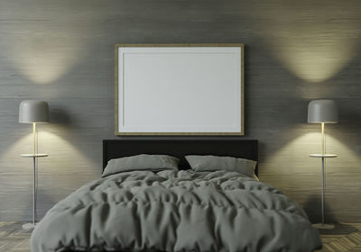 Illuminated electric lamp on bed against wall at home