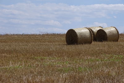 Hay bales on field against sky