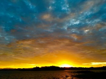 Scenic view of dramatic sky over lake during sunset