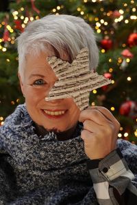 Portrait of a smiling midaged woman holding christmas star during winter