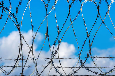 Low angle view of chainlink fence against blue sky