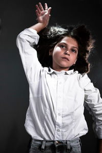 Portrait of young woman standing against black background