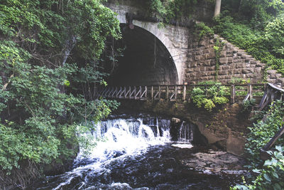 Arch bridge over river with buildings in background