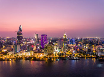 Illuminated city at waterfront during sunset