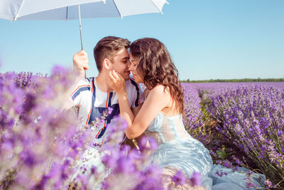 A couple in love under a white umbrella on a lavender field love