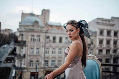 Portrait of beautiful woman standing against buildings in city