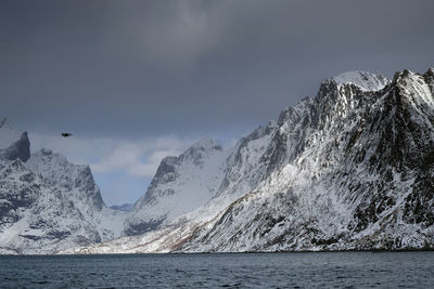 Scenic view of snowcapped mountains by sea against sky