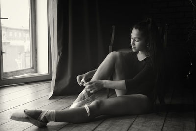 A young gentle and thoughtful ballerina poses in the interior and at the window