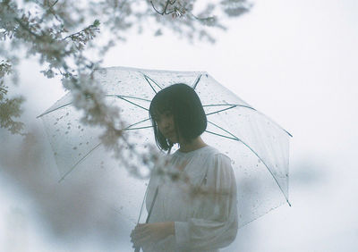 Rear view of woman standing on cross against trees